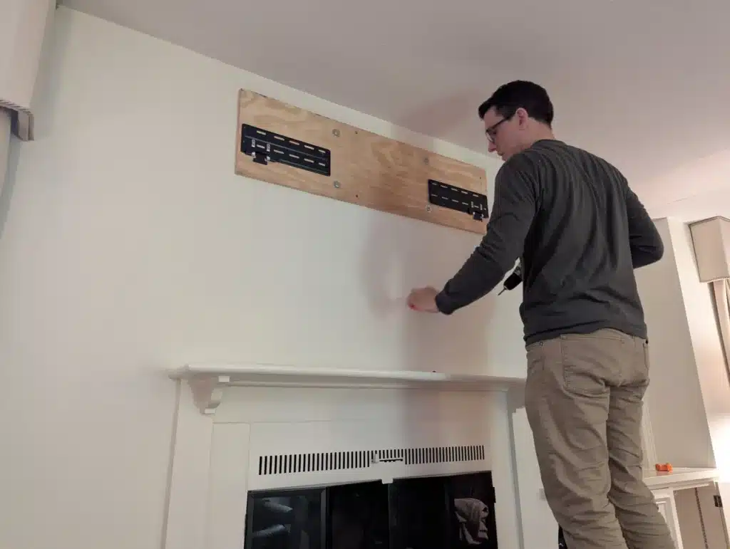 Horus Community Services technician installing a wood backer board above a fireplace for a TV mount in Trumansburg, NY