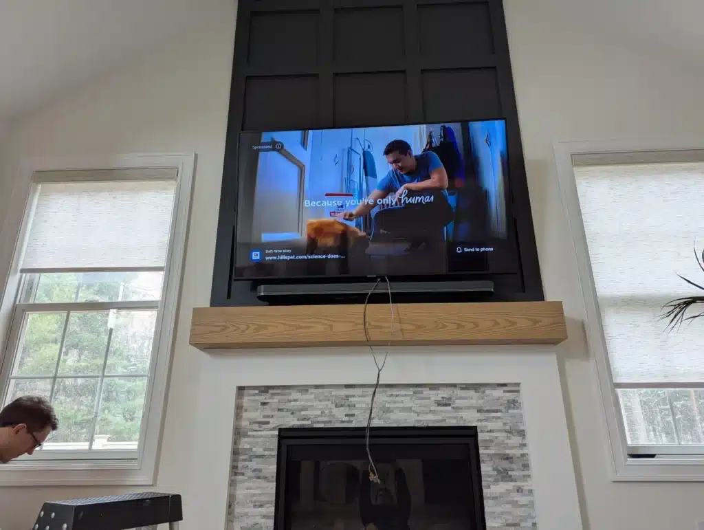 Completed TV installation on a stone-fireplace accent wall in a vaulted Trumansburg, NY living room by Horus Community Services
