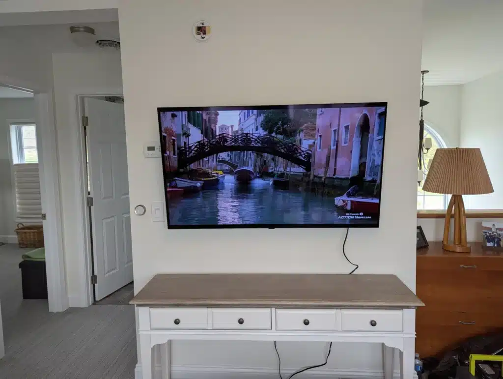 Completed wall-mounted TV above a console table in a bright living room by Horus Community Services in Trumansburg, NY