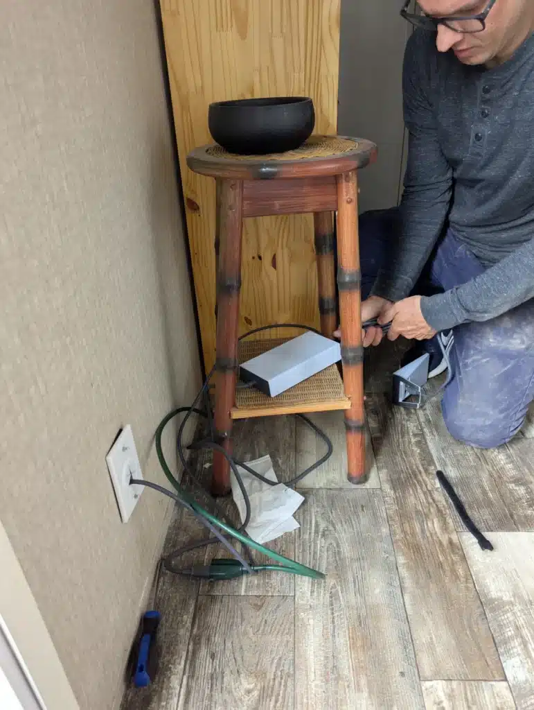 Horus Community Services technician routing an ethernet cable to a wall jack in Trumansburg, NY