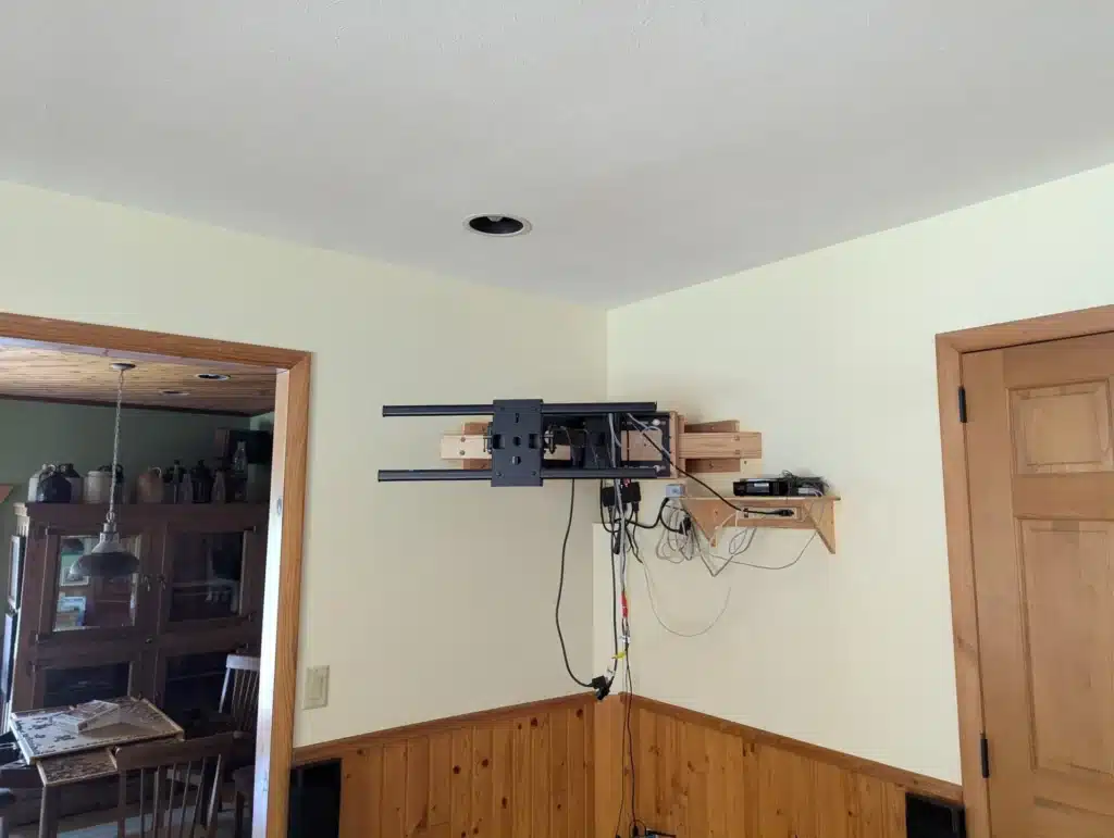 Heavy-duty articulating TV mount installed in a room corner with concealed wiring by Horus Community Services in Trumansburg, NY