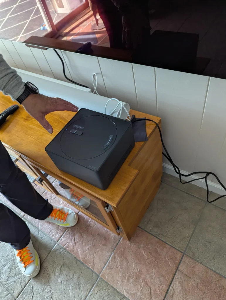 Audio video receiver set up on a wooden media console beneath a wall-mounted TV by Horus Community Services in Trumansburg, NY