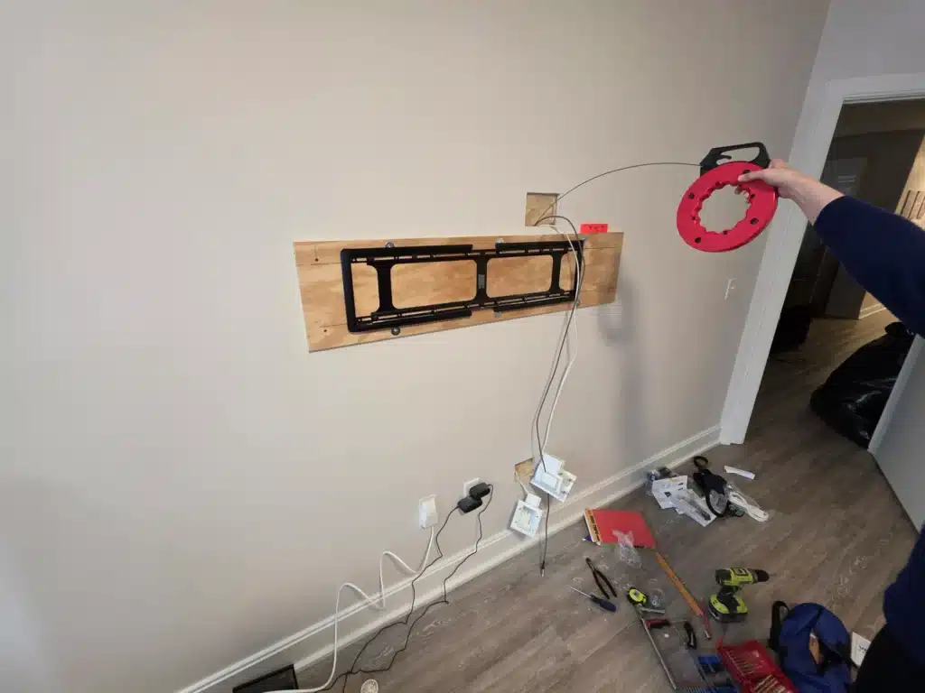 Horus Community Services technician fishing cable inside a wall for a concealed TV mount in Trumansburg, NY