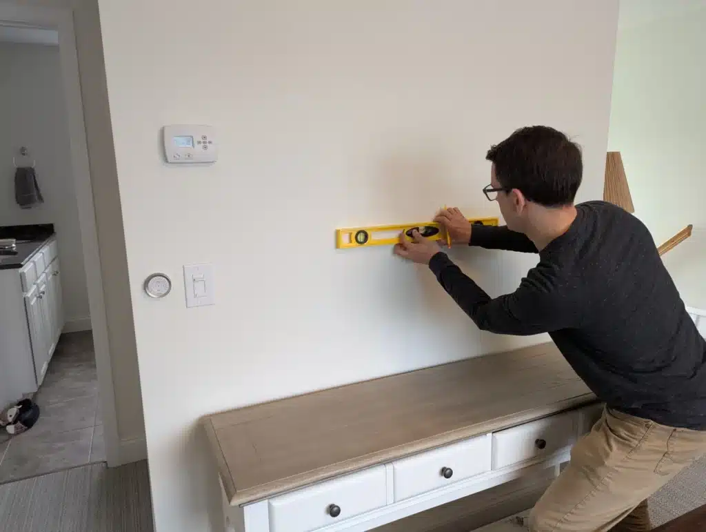 Horus Community Services technician leveling a wall above a credenza for a TV mount in Trumansburg, NY