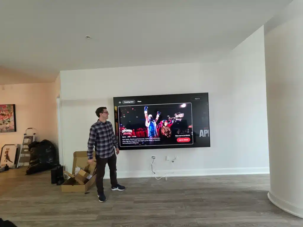 Wall-mounted TV in a spacious open-concept living room installed by Horus Community Services in Trumansburg, NY