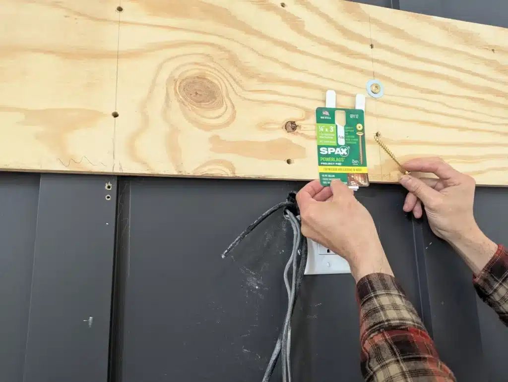 Horus Community Services technician installing a recessed cable plate on a plywood backer board for a clean TV install in Trumansburg, NY