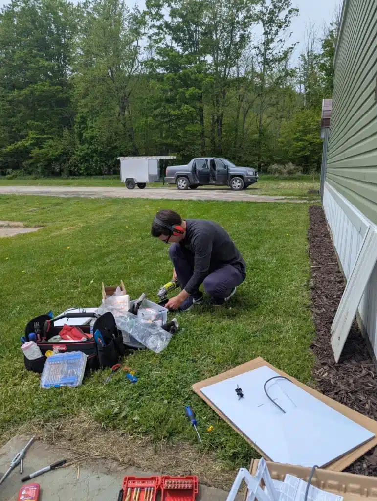 Horus Community Services technician assembling satellite internet equipment on a lawn in Trumansburg, NY