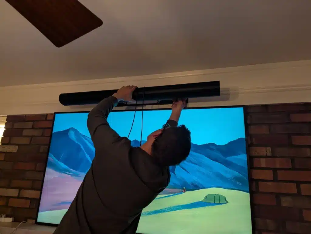 Horus Community Services technician installing a soundbar on a brick-fireplace mounted TV in Trumansburg, NY
