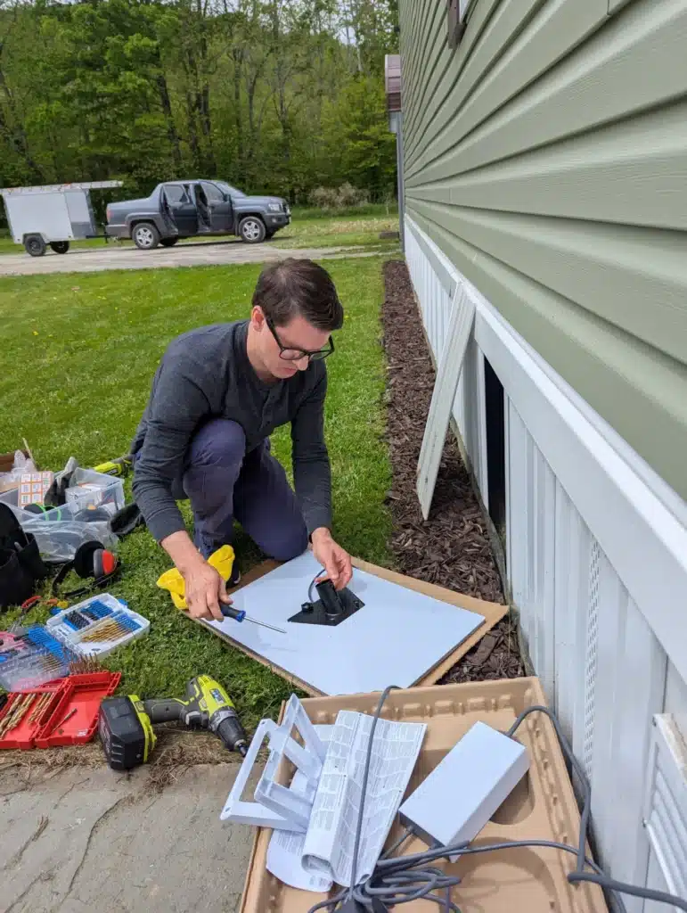 Horus Community Services technician assembling a Starlink satellite dish outside a home in Trumansburg, NY
