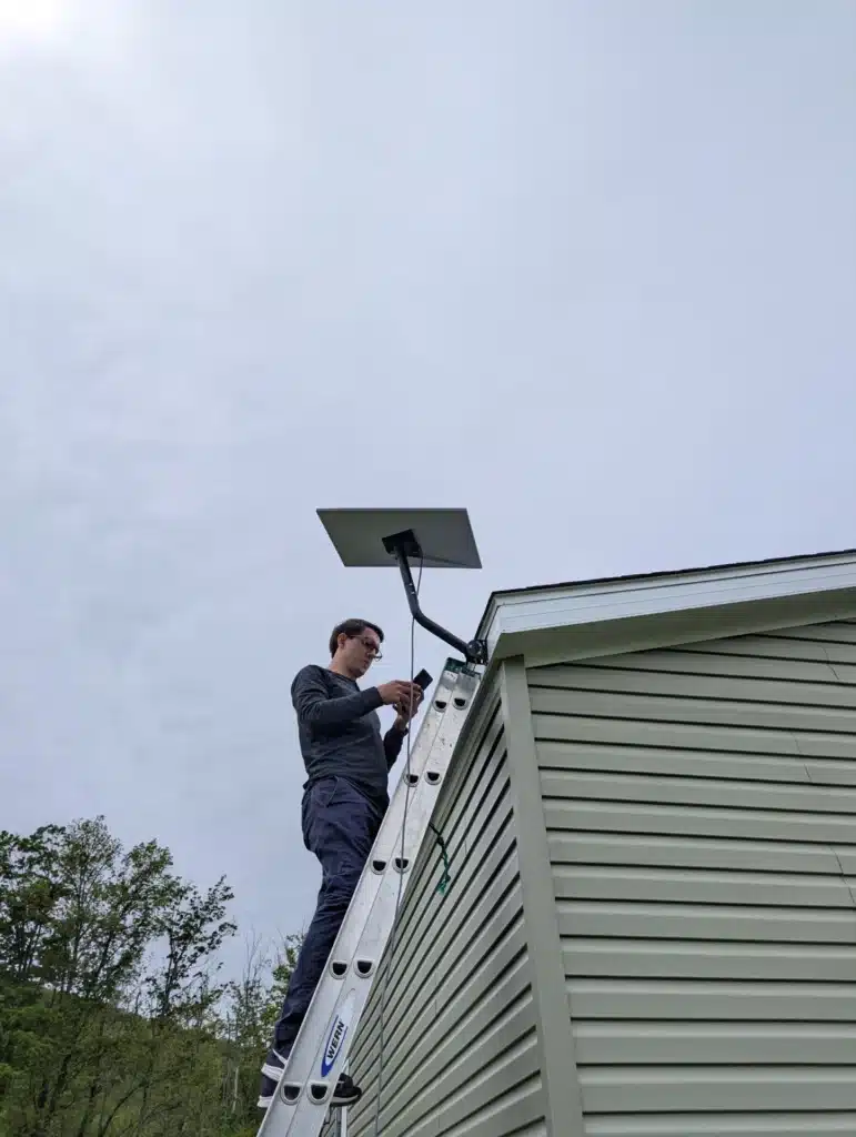 Horus Community Services technician installing a Starlink satellite dish on a home roofline in Trumansburg, NY