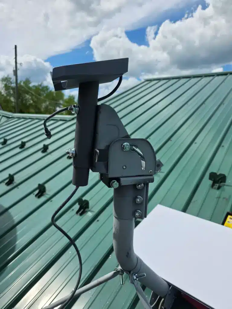 Starlink mount positioned beside an existing satellite dish on a metal roof by Horus Community Services in Trumansburg, NY