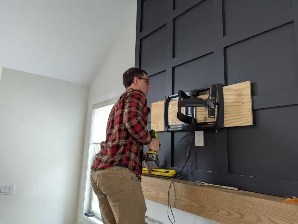 Horus Community Services technician attaching a TV mount bracket to a board-and-batten accent wall in Trumansburg, NY