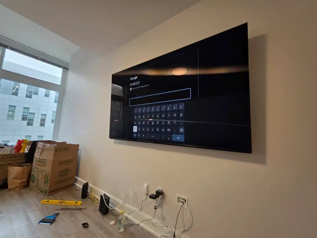 Newly wall-mounted TV during setup in a modern Trumansburg, NY condo by Horus Community Services